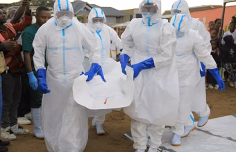 Healthcare workers in protective equipment carry the body of doctor Victor Kingombe during his funeral in Kisangani